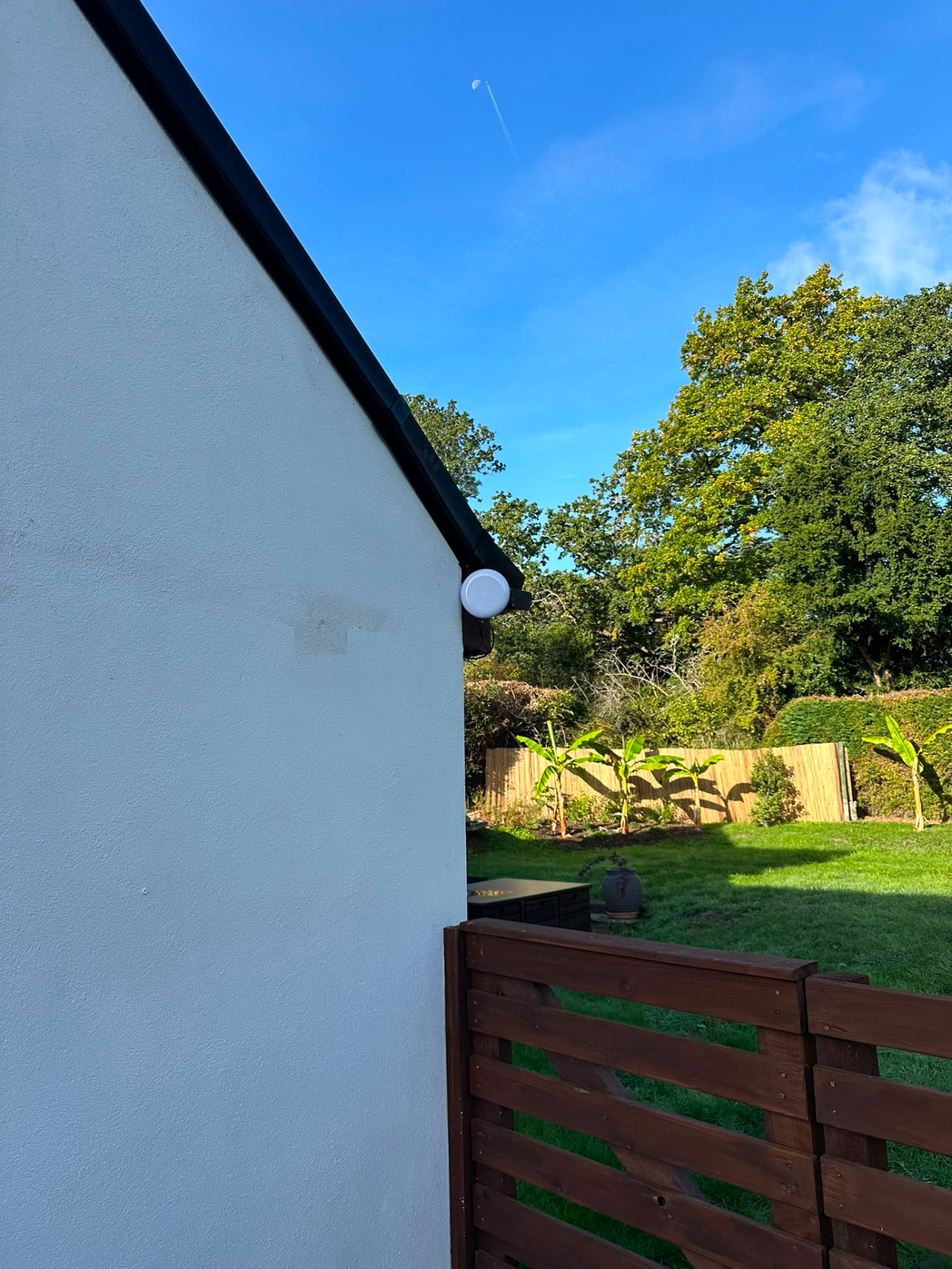 Outdoor wireless unit mounted at the edge of the building overlooking the garden
